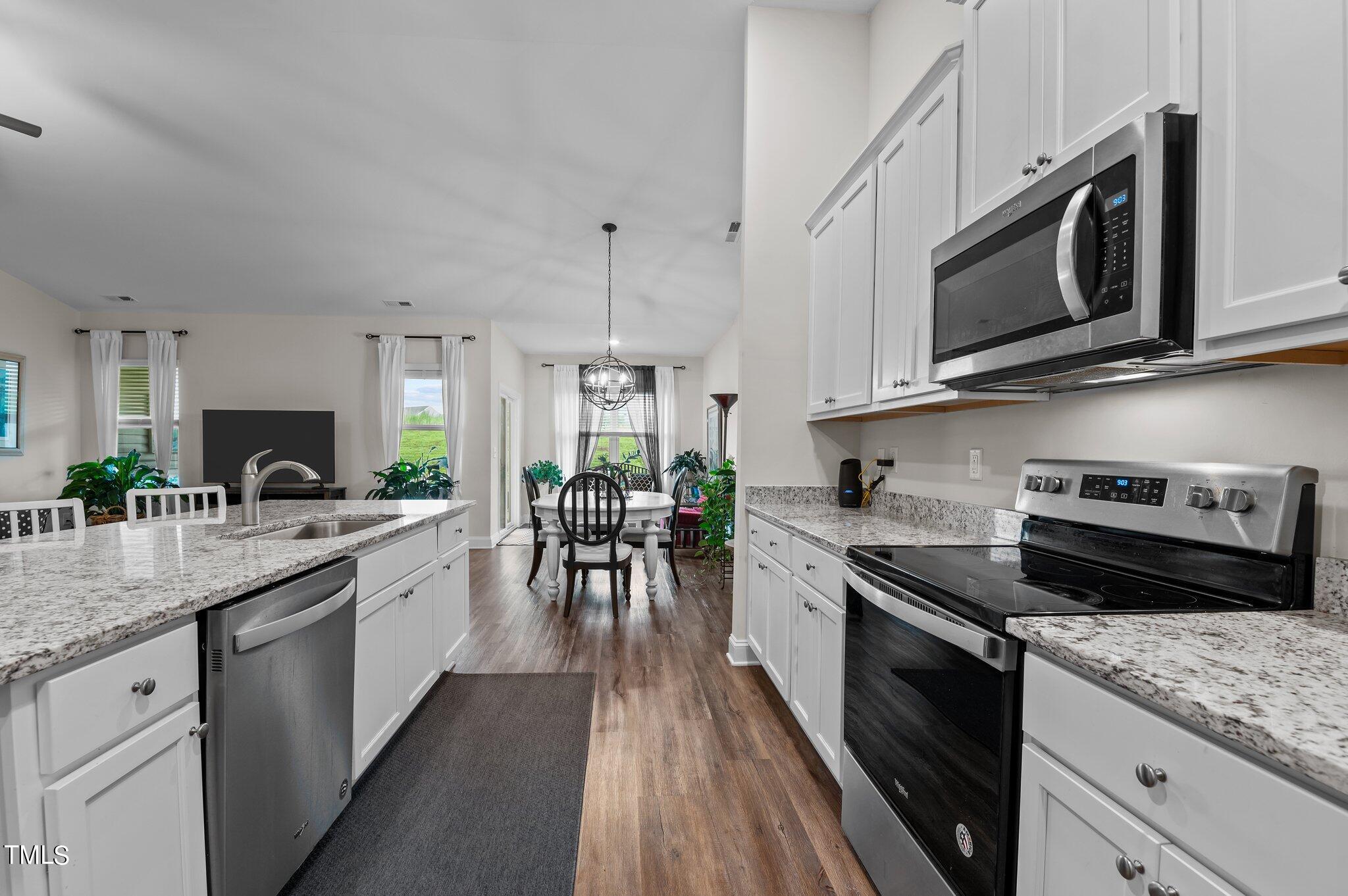 Furnished kitchen with granite island and stainless appliances opening to a dining area.