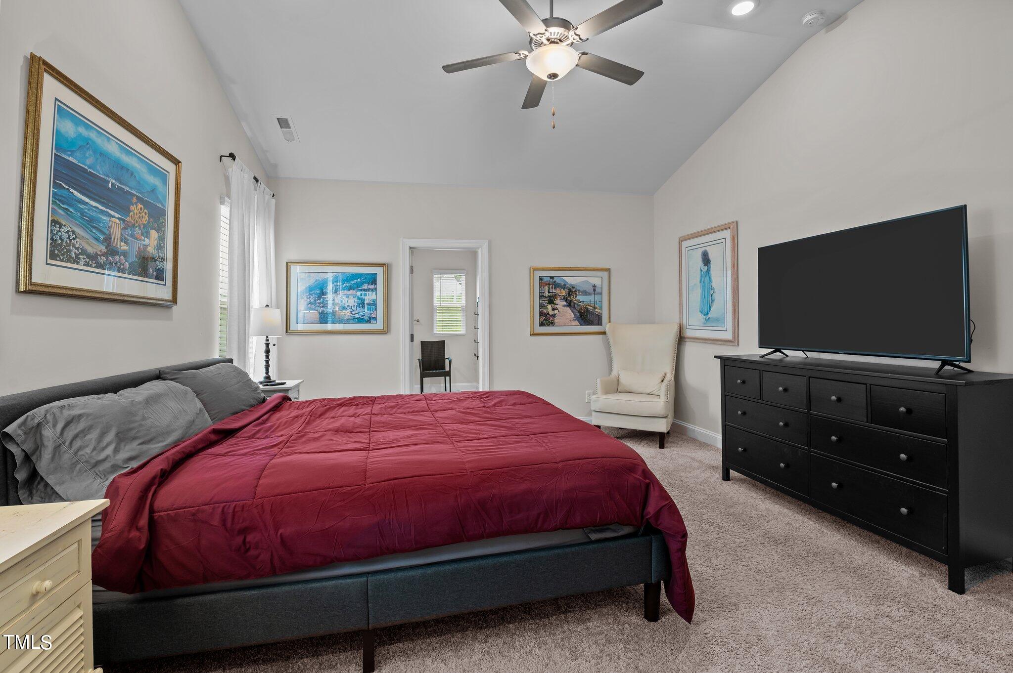 Furnished bedroom with a burgundy bedspread, gray pillows, and a large television.