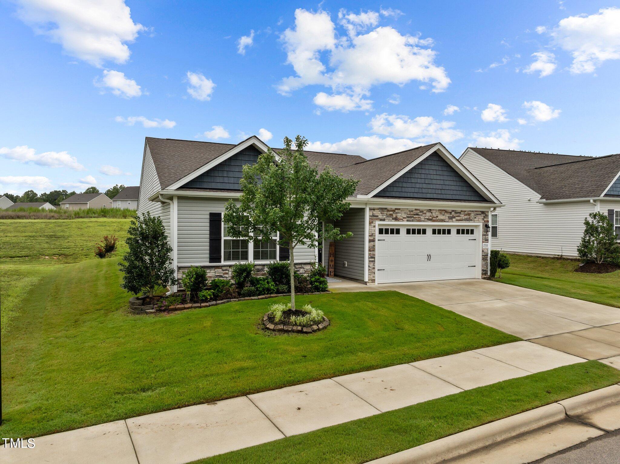Single-story gray house with stone-accented garage, landscaped front lawn, and concrete driveway.