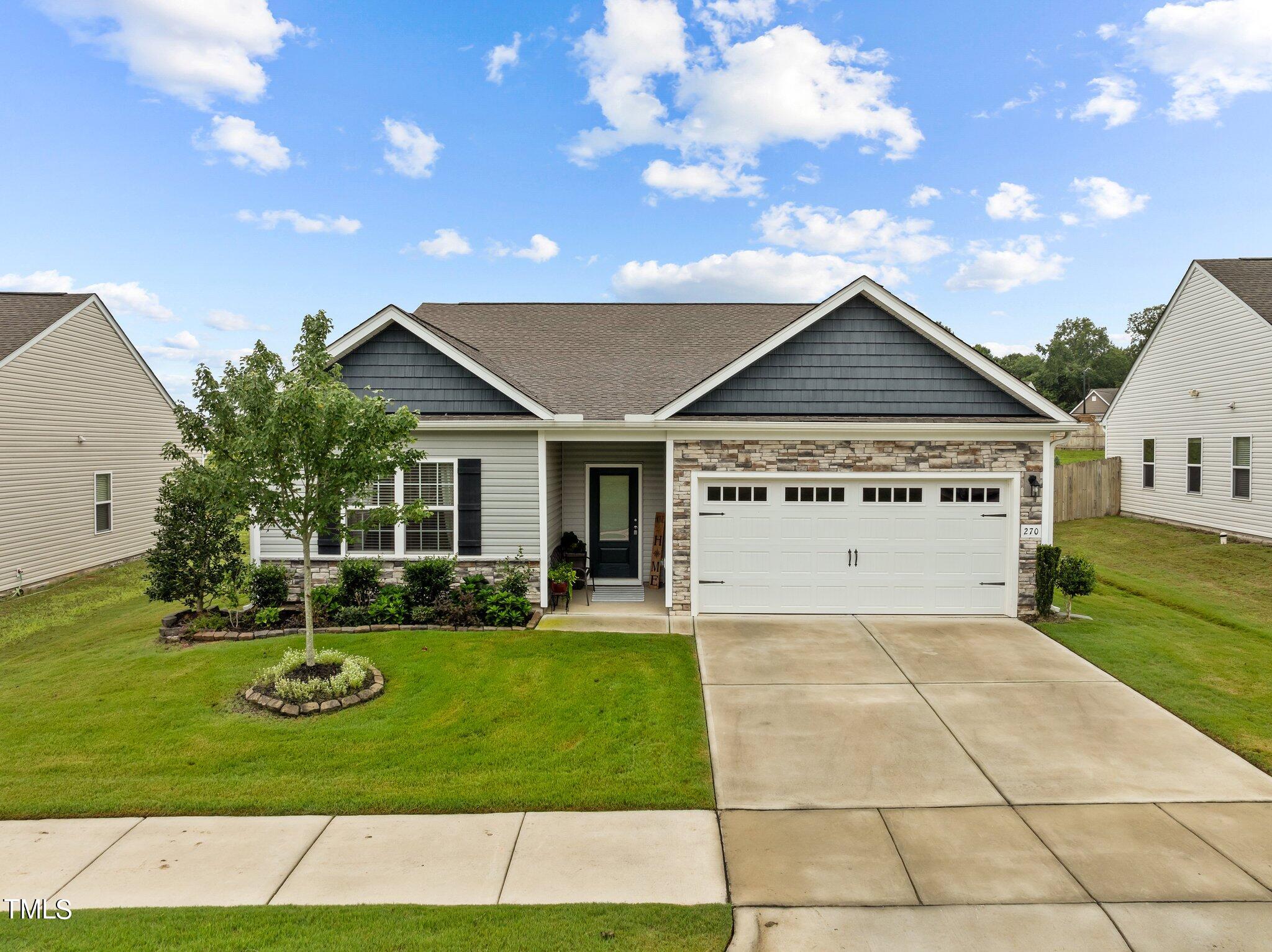 One-story gray home with stone-accented garage, covered entry, and landscaped front lawn.
