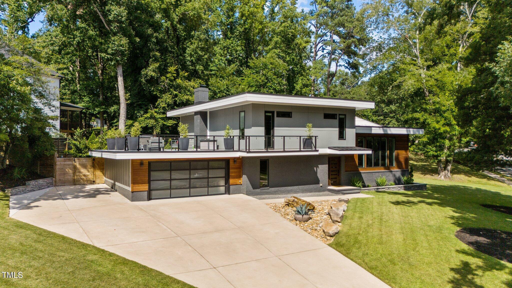Modern two-story home with a rooftop terrace, wood accents, and a broad driveway.