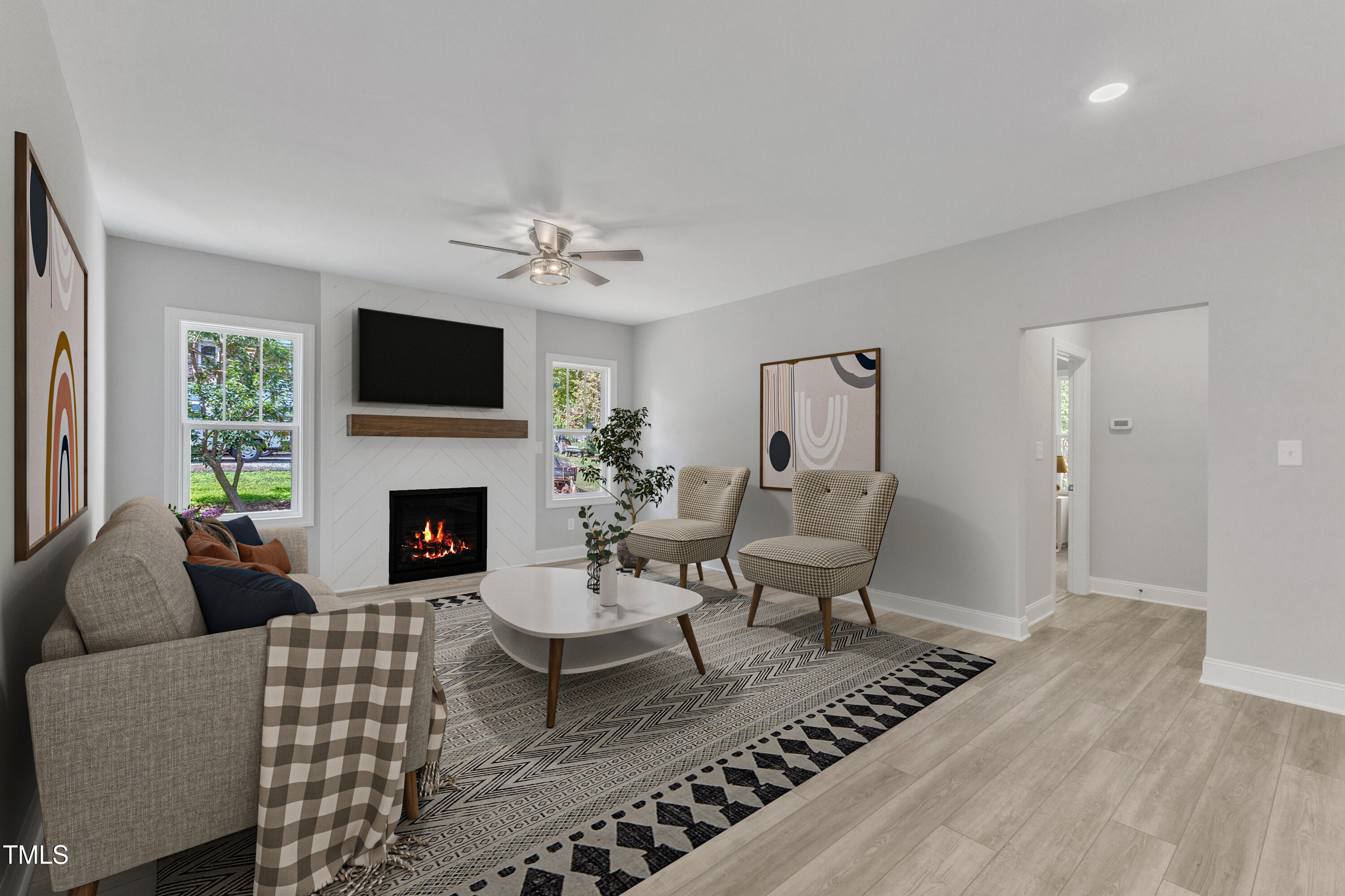Furnished living room with a fireplace, wall-mounted television, accent chairs, and a large patterned rug.