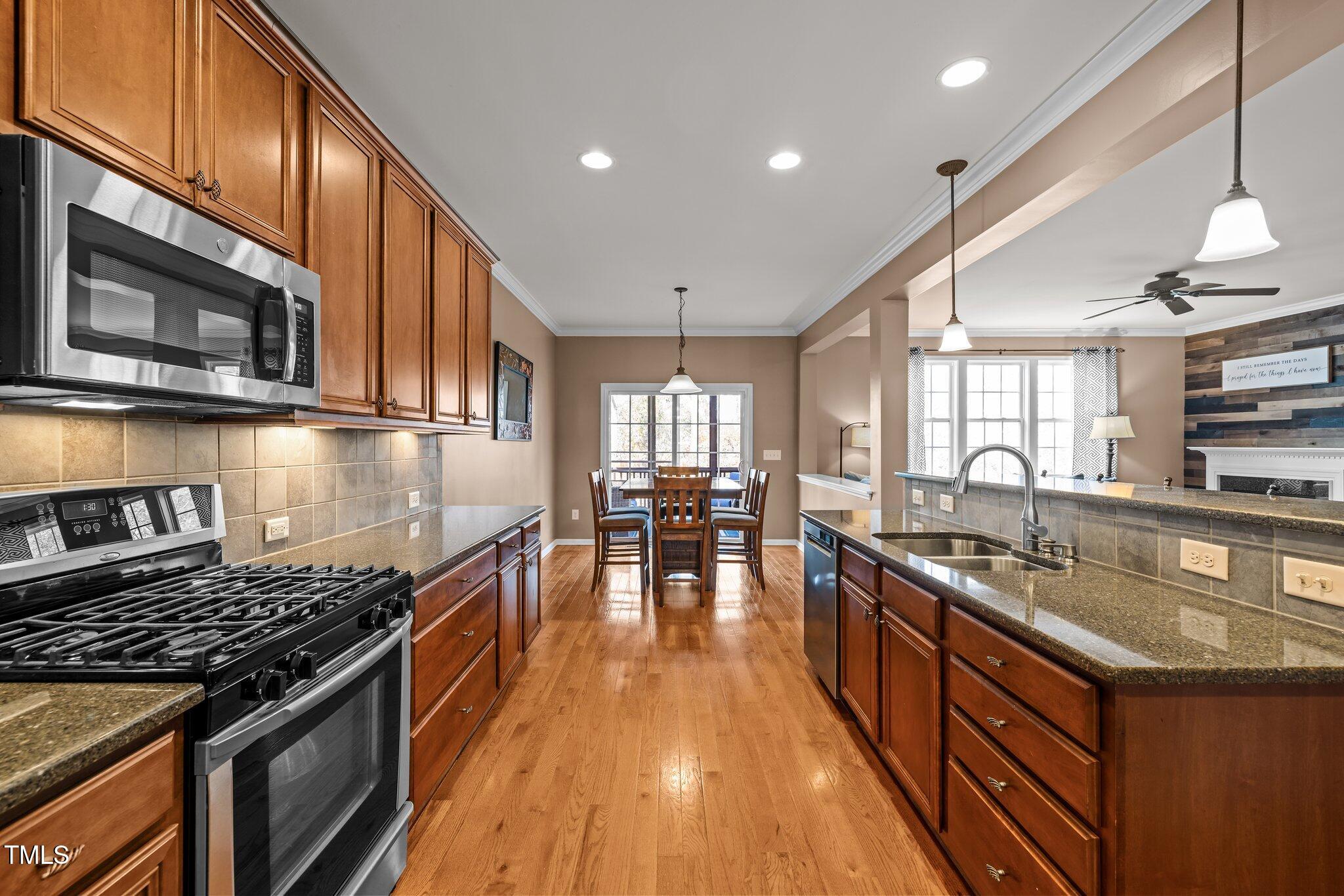 Kitchen with warm wood cabinets and granite counters opening to a dining area and living room.