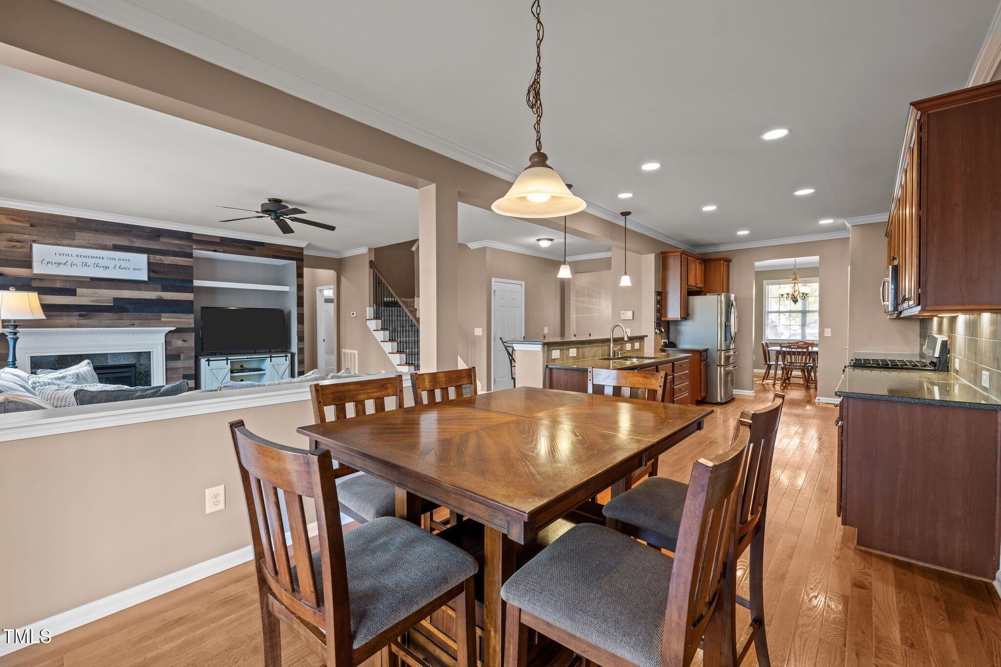 Dining room with a large wooden table, open to a kitchen and living room with a fireplace.