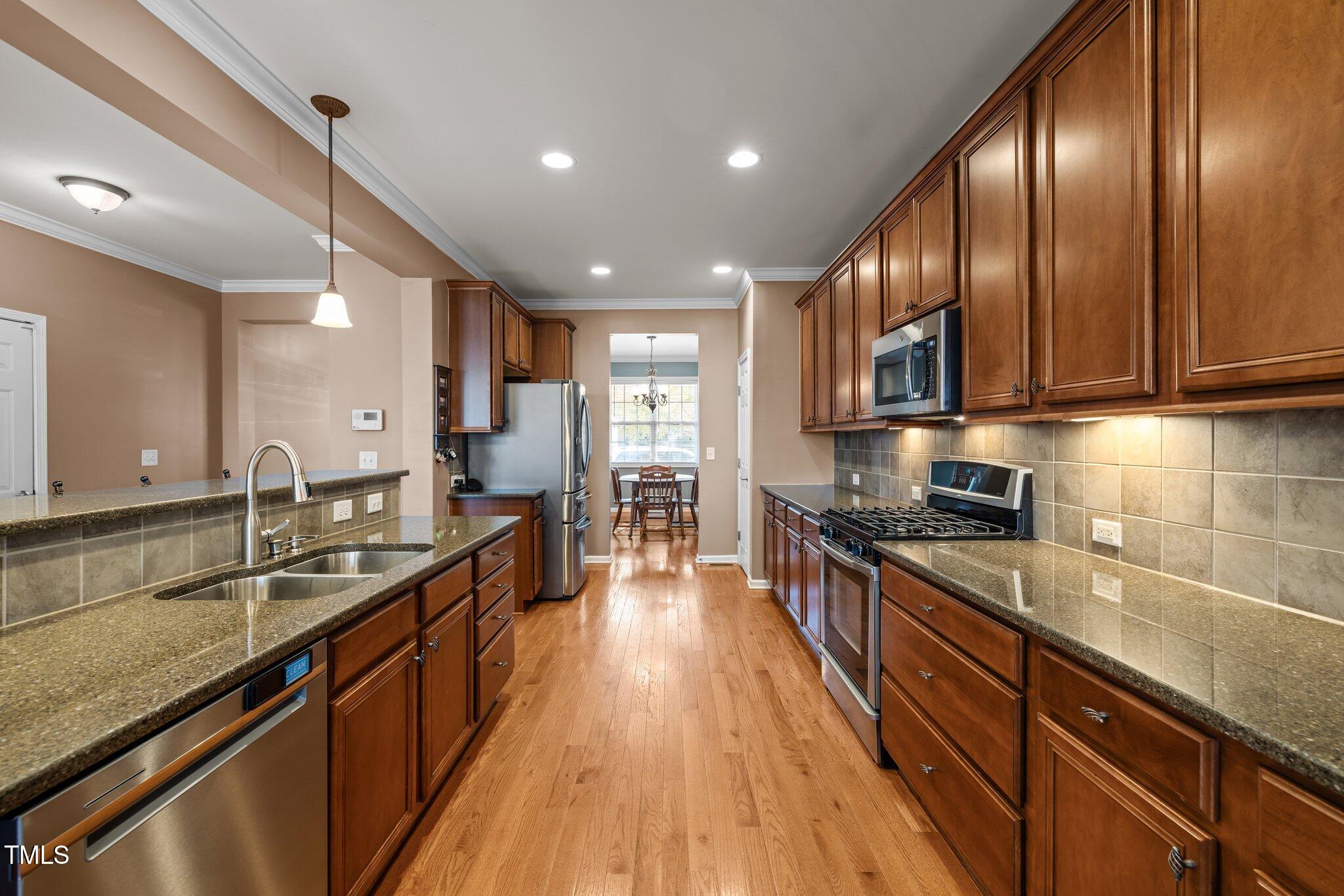 Kitchen with dark wood cabinets, granite counters, stainless steel appliances, and hardwood floors.