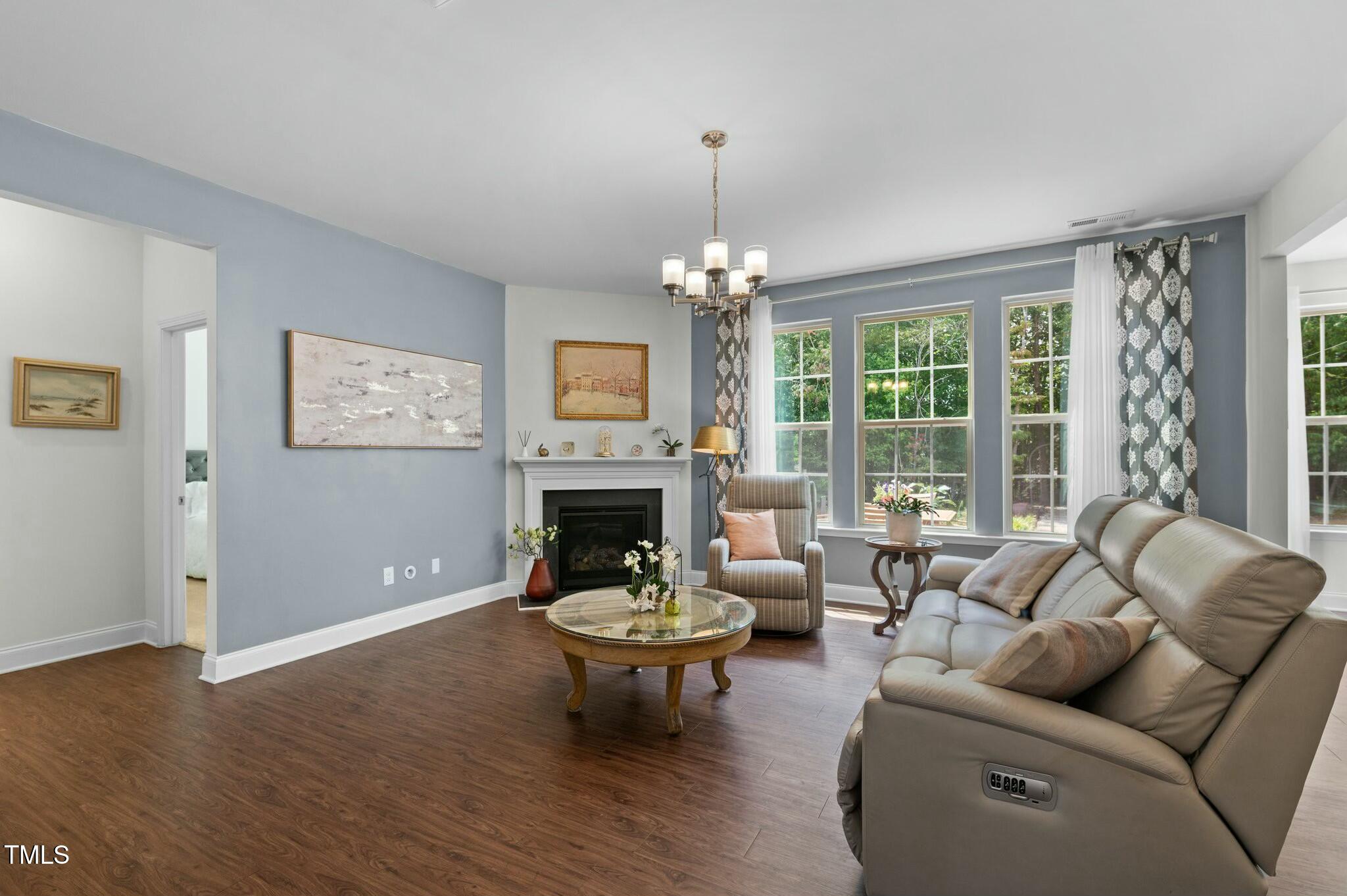 Living room with fireplace, large garden-facing windows, and a leather reclining sofa.