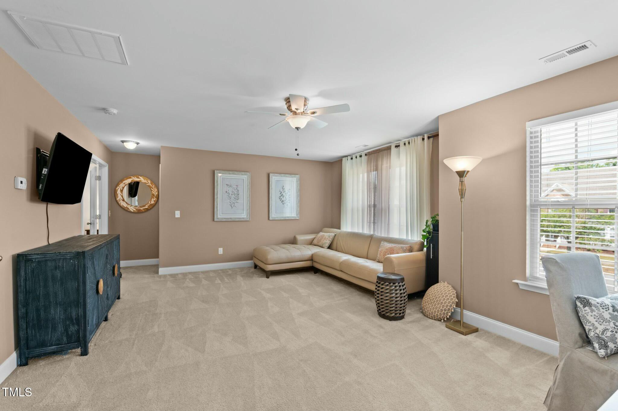 Living room with a beige sectional, ceiling fan, and wall-mounted television.