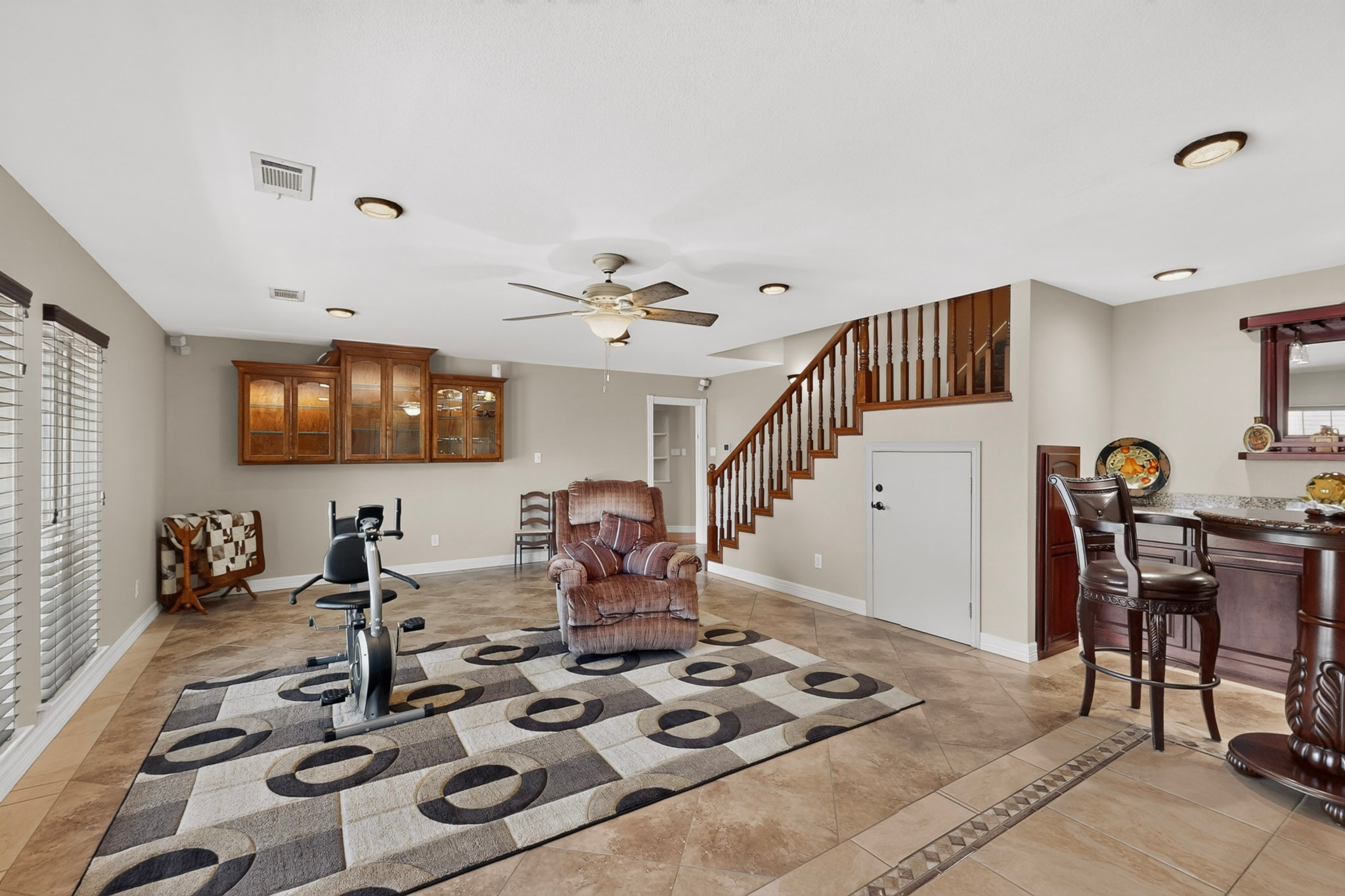 Living area with a wooden staircase, recliner, exercise bike, and bar counter.