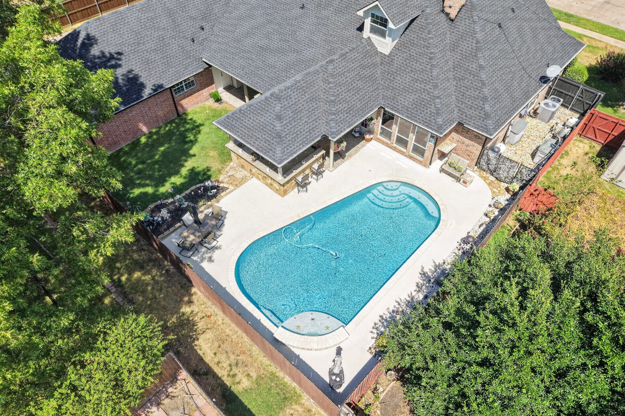 Aerial view of a brick home with a large backyard pool and surrounding patio.