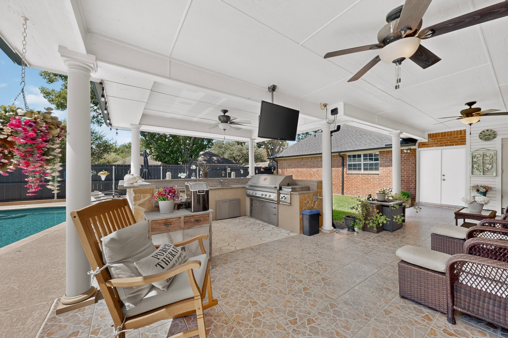 Covered patio with an outdoor kitchen and grill beside a swimming pool.