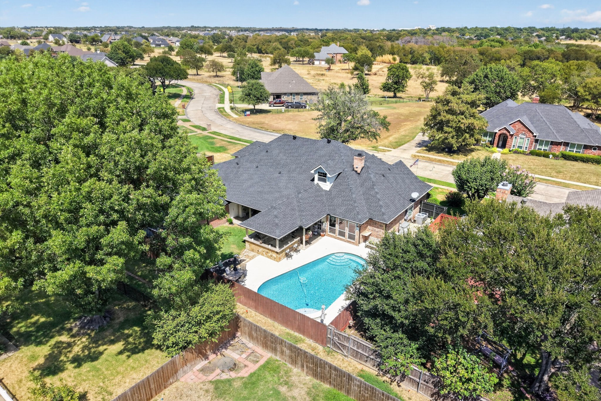 Aerial view of a brick home with a fenced backyard and swimming pool.