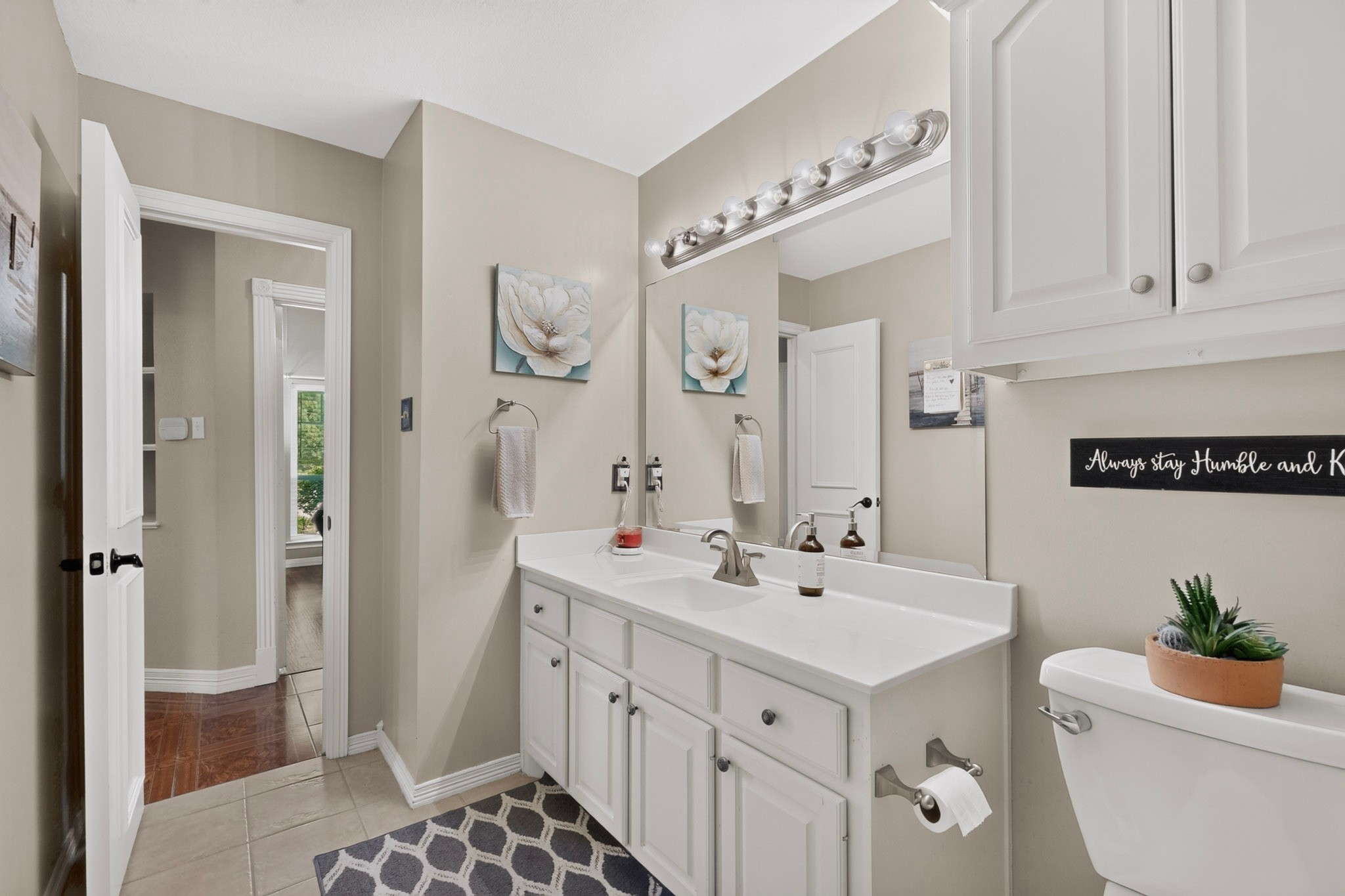 Bathroom with a long white vanity, large mirror, and vaulted ceiling.