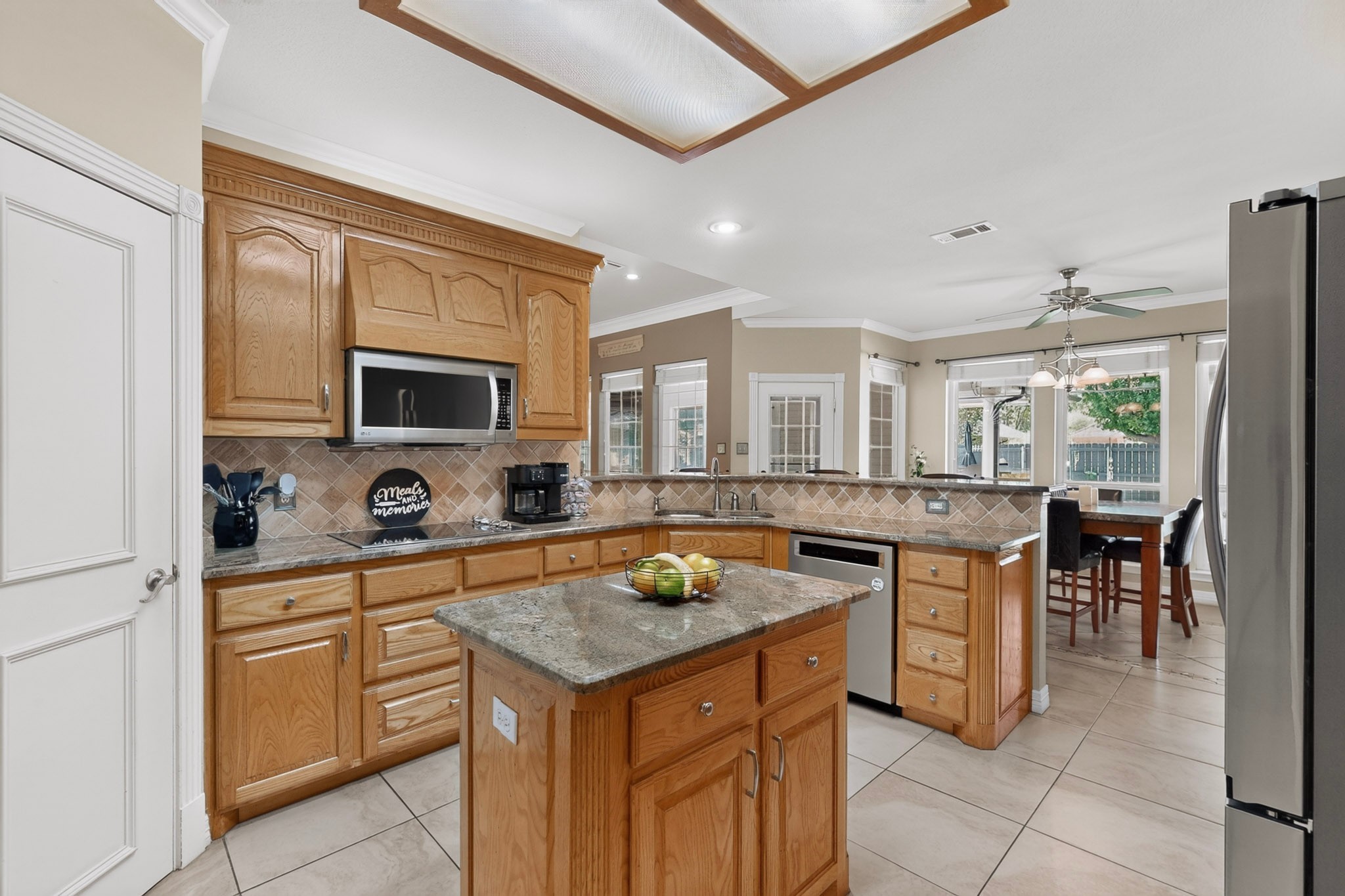 Kitchen with a granite-topped island, honey-colored cabinets, and an open dining area.