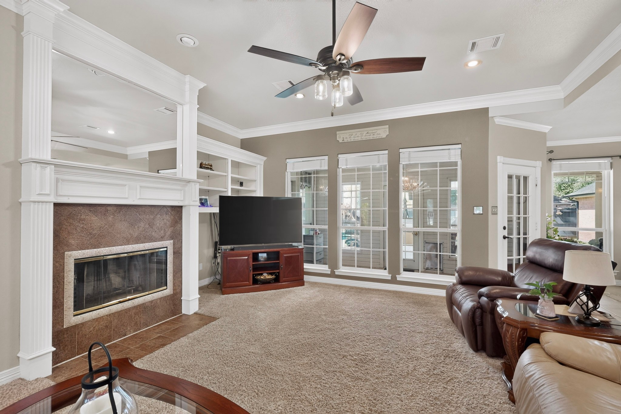 Living room with a tiled fireplace, built-in shelving, and large windows.