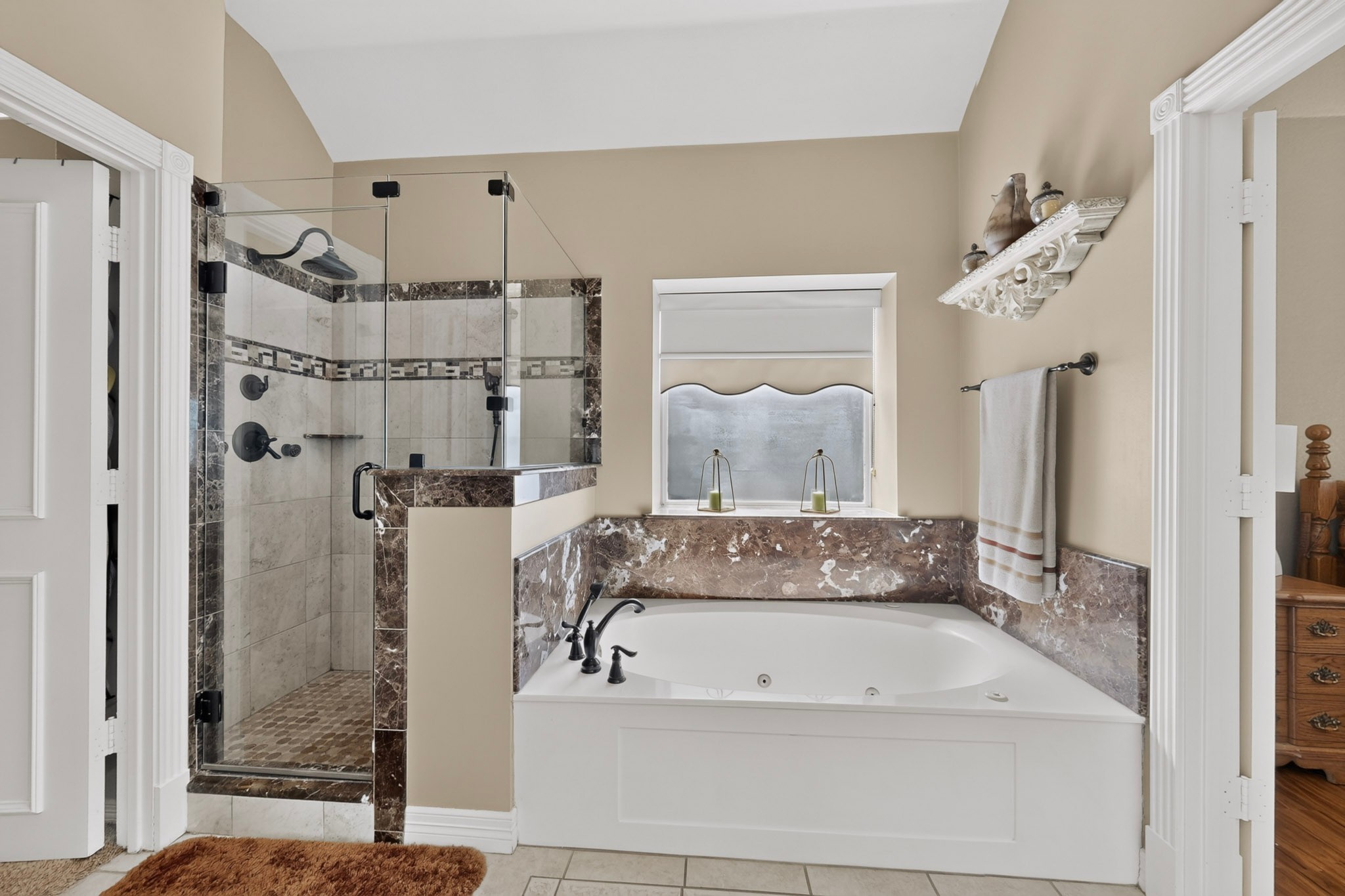 Bathroom with a jetted soaking tub beside a glass-enclosed tiled shower.