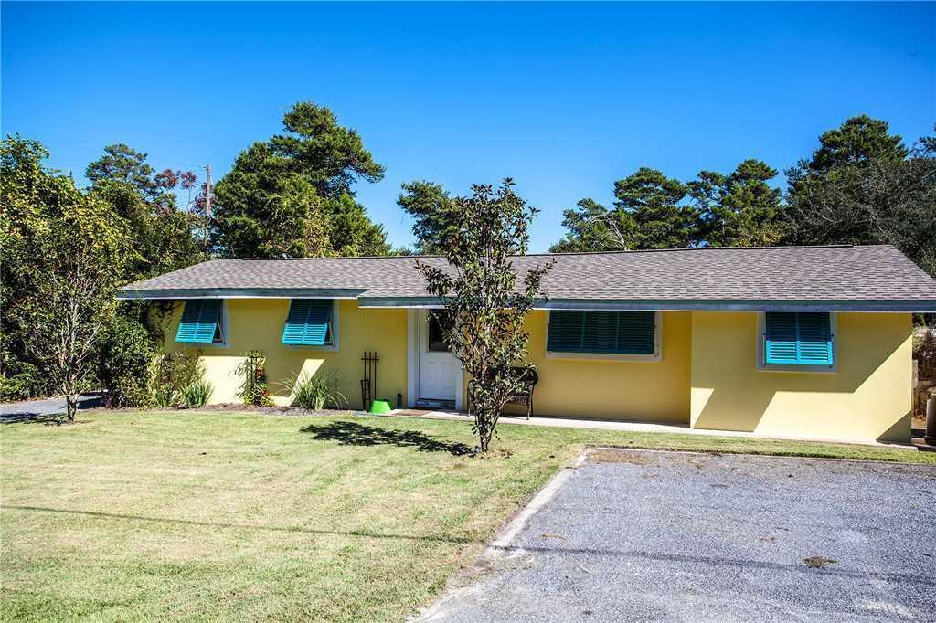 Single-story yellow house with bright blue shutters, front lawn, and paved driveway.