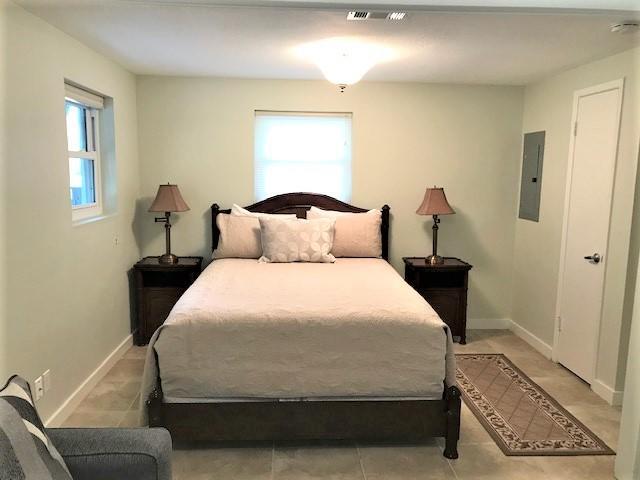 Bedroom with a dark wood bed, pale bedding, matching nightstands, and tiled floor.