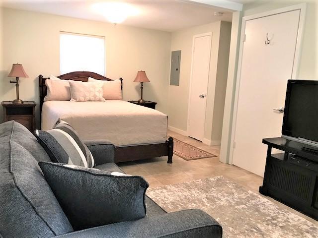 Bedroom with a dark wood bed, pale bedding, and blue-gray sofa.