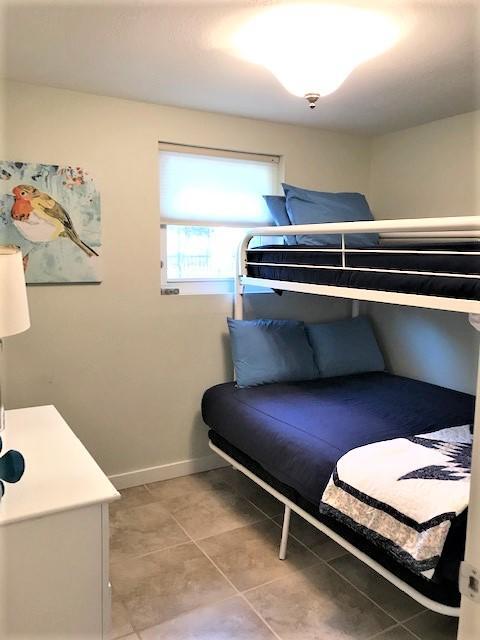 Small bedroom with a black metal bunk bed, blue bedding, tiled floor, and bird artwork.