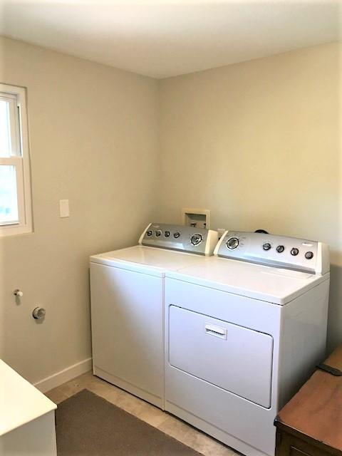 Laundry room with a white washer and dryer beside a small window.