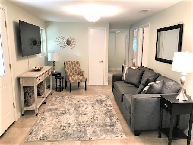 Living room with a gray sofa, patterned accent chair, and pale area rug.