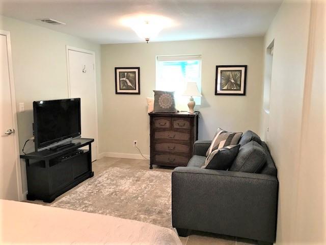 Living room with a gray sofa, television, wooden dresser, and light patterned rug.