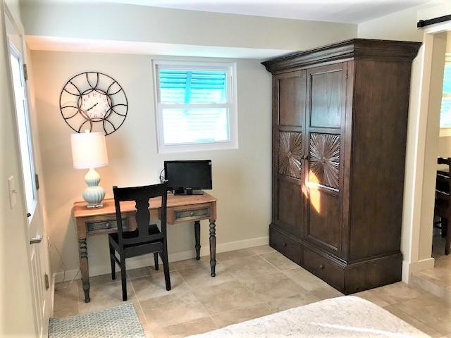 Home office with a wooden desk, wall clock, and large dark wood armoire.
