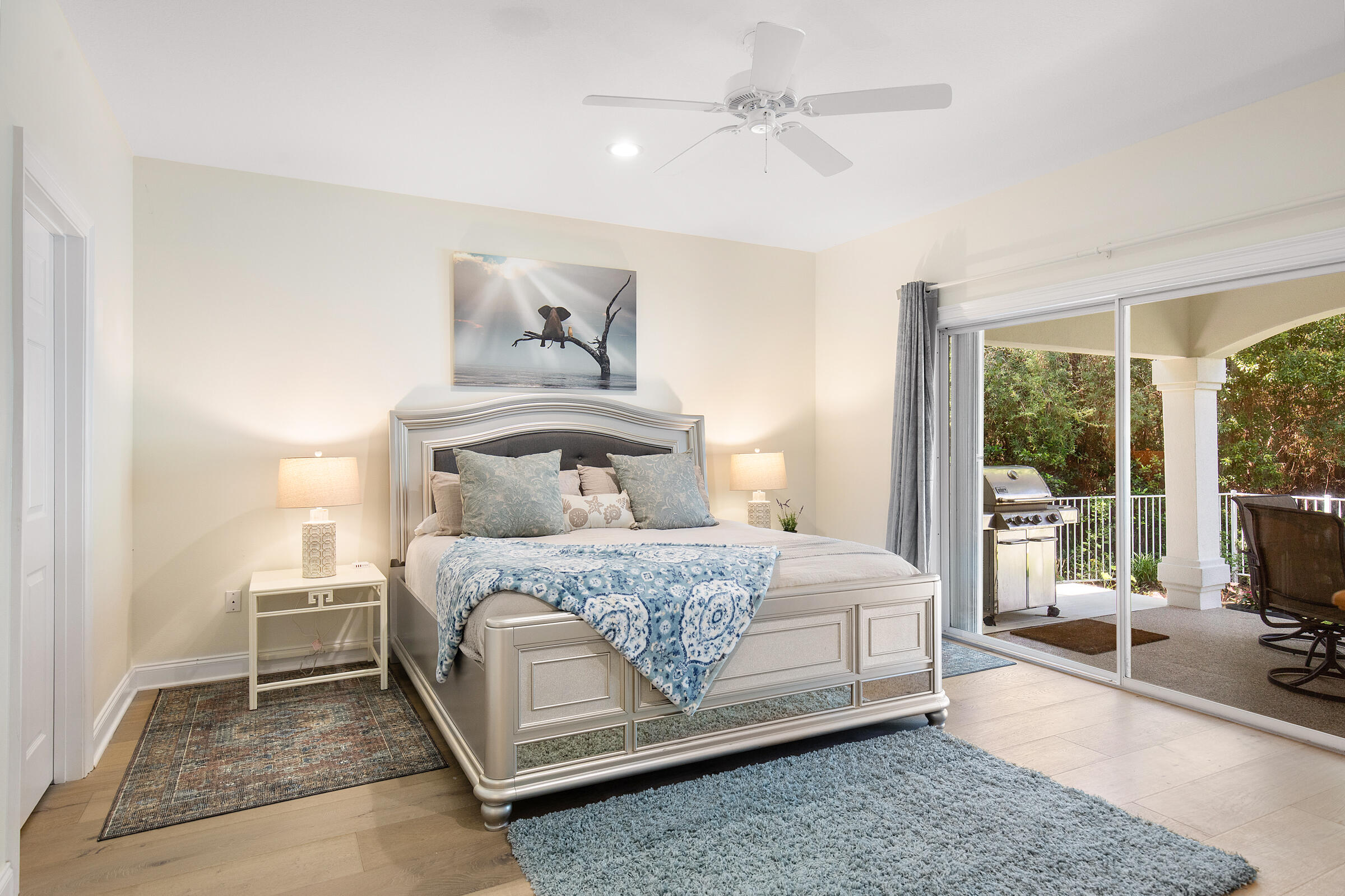 Bedroom with a silver-framed bed and blue bedding beside sliding doors to a covered patio.