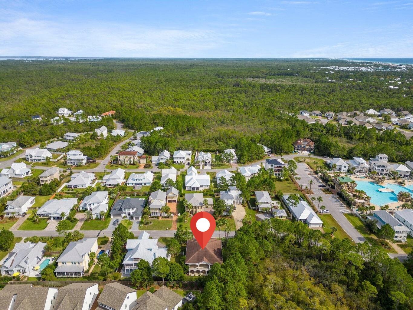 Aerial neighborhood view with a red marker pinpointing a home near a community pool.