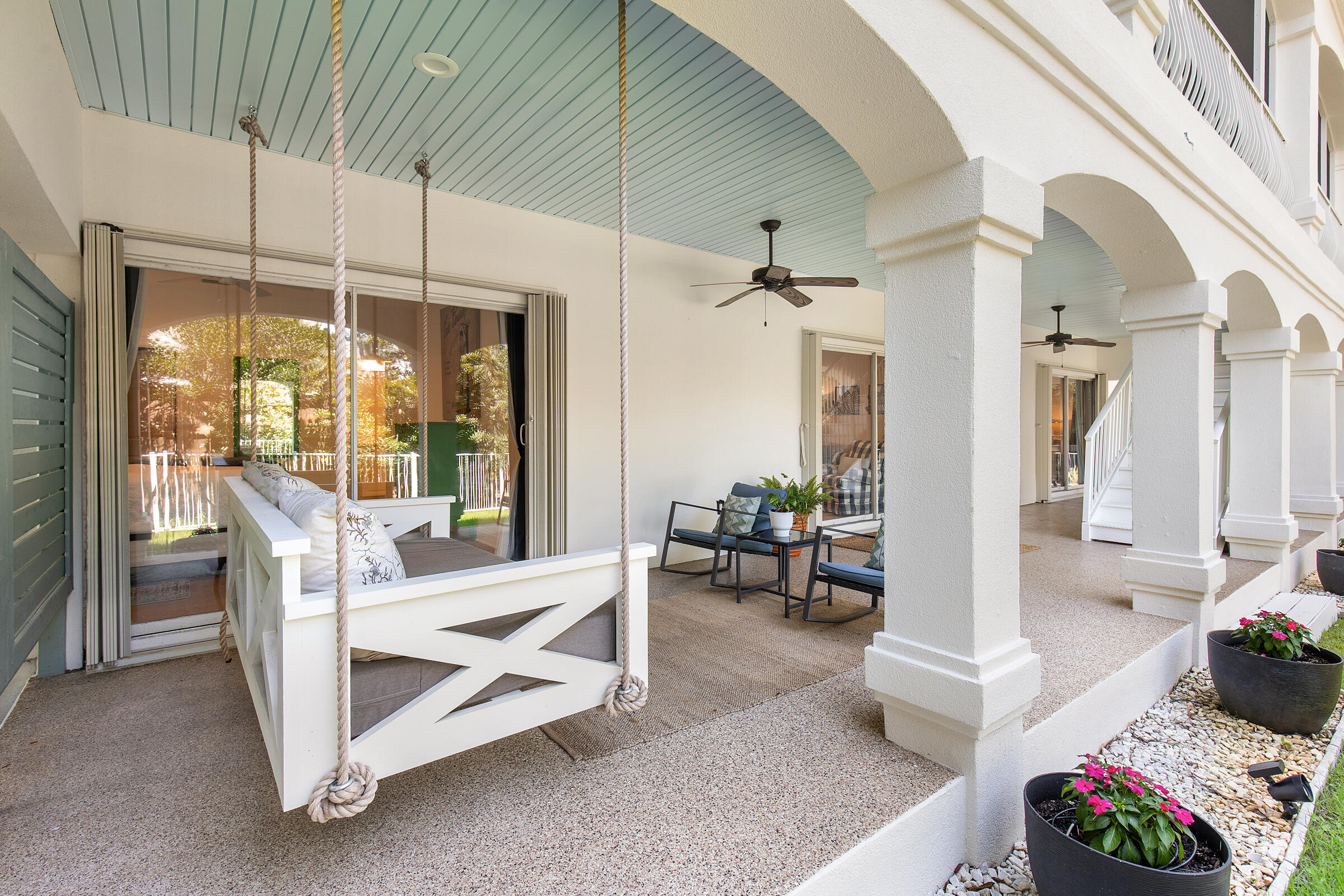 Covered porch with a rope-hung swing, white arches, and blue ceiling.