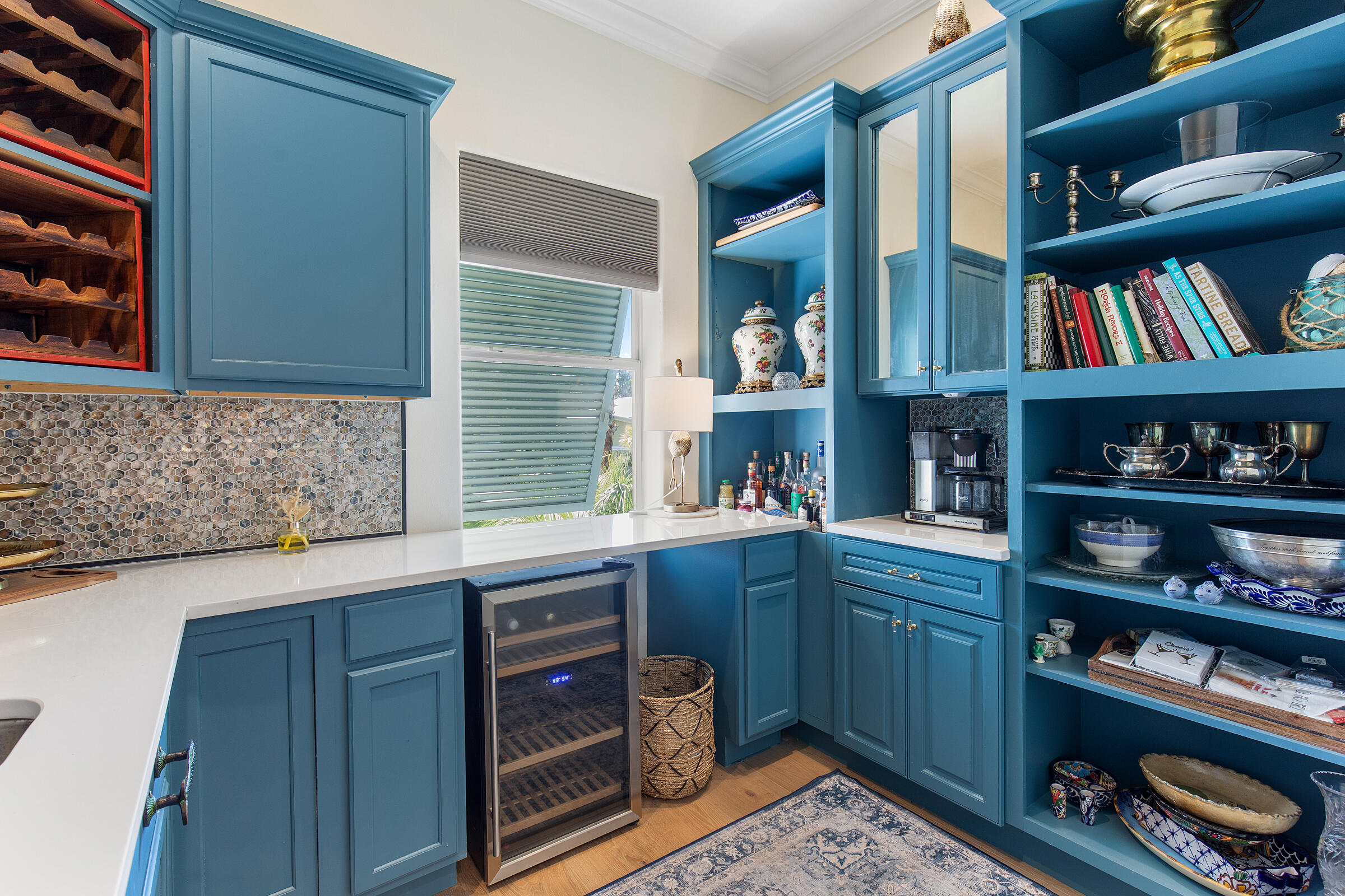 Wet bar with blue built-in cabinets, open display shelves, and a wine refrigerator.