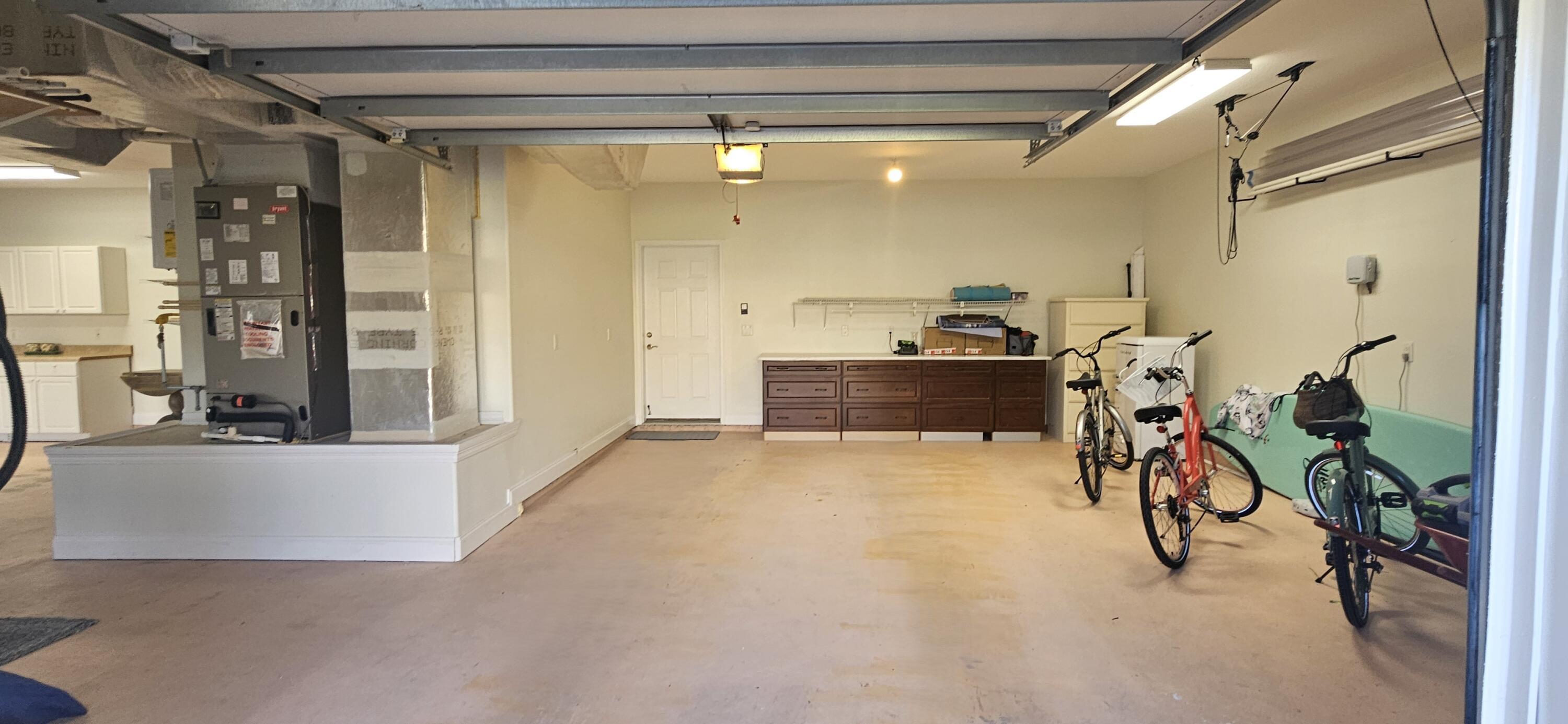 Garage with storage cabinets, a water heater, and several bicycles.