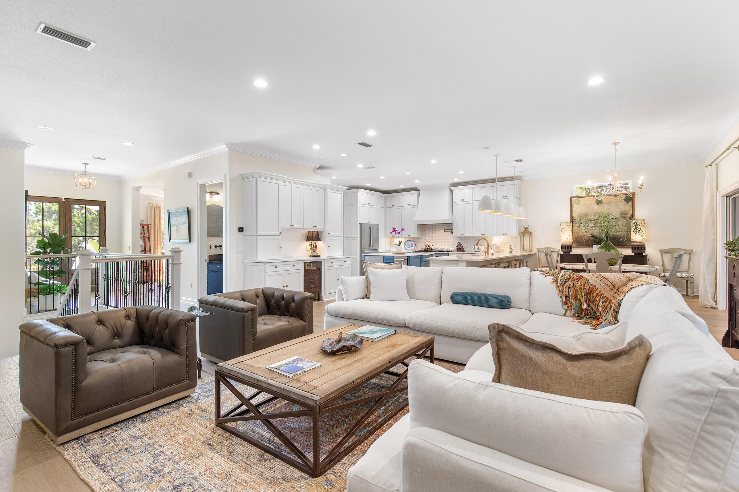 Open-concept living room with a large white sectional, adjoining kitchen, and dining area.