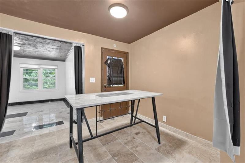 Interior room with a narrow marble-top table, tiled floors, and an adjoining windowed room.