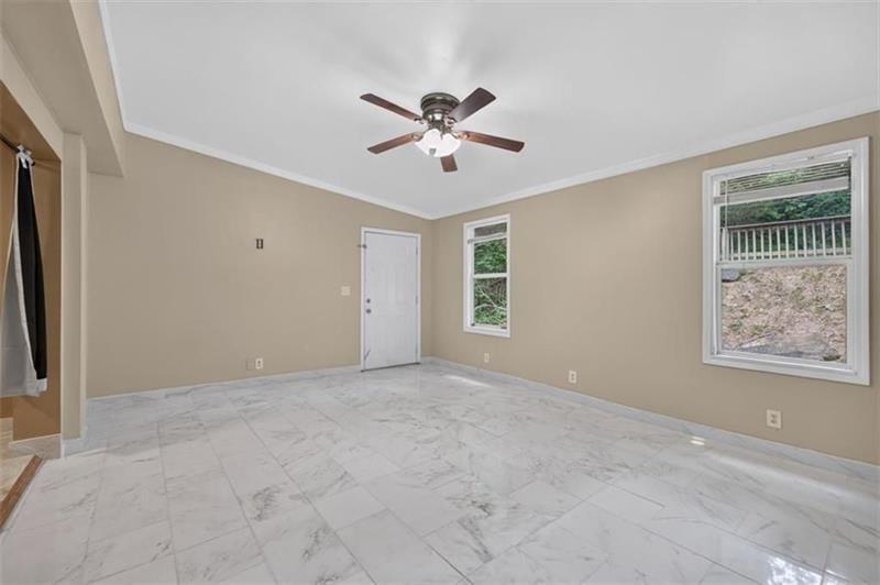 Vacant bedroom with marble-look tile flooring, a ceiling fan, and two windows.