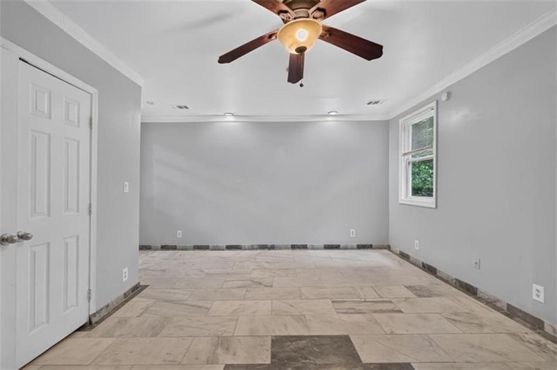 Empty room with a tiled floor, ceiling fan, and window with blinds.