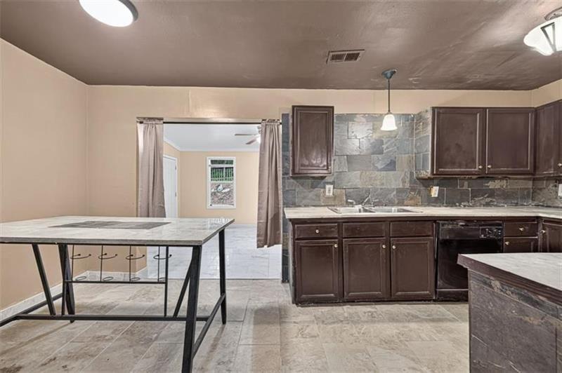 Kitchen with dark wood cabinets, a stone backsplash, and a freestanding island.