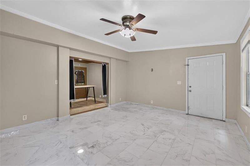 Unfurnished room with marble-look tile flooring and a ceiling fan.