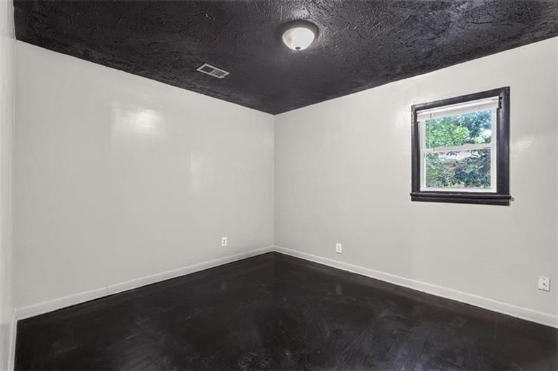 Empty room with a dark ceiling and floor and a window with dark trim.
