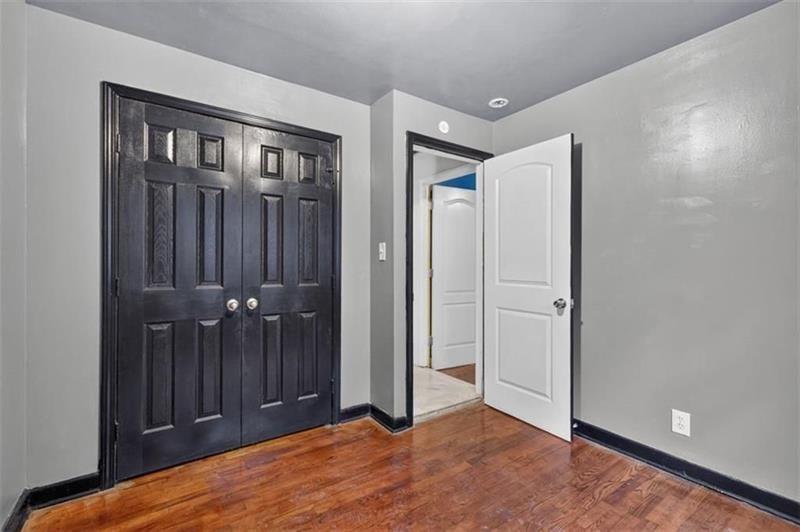 Unfurnished room with polished hardwood floors, dark double closet doors, and an open white door.