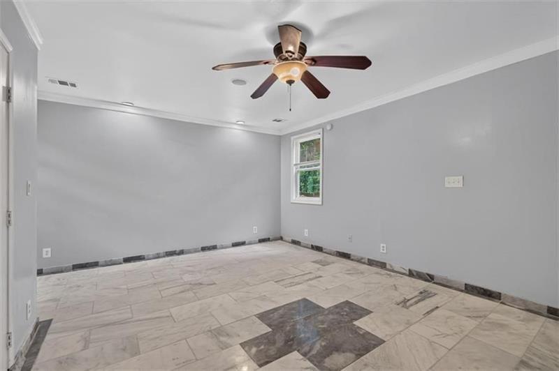 Empty room with patterned tile flooring, gray walls, and a dark ceiling fan.