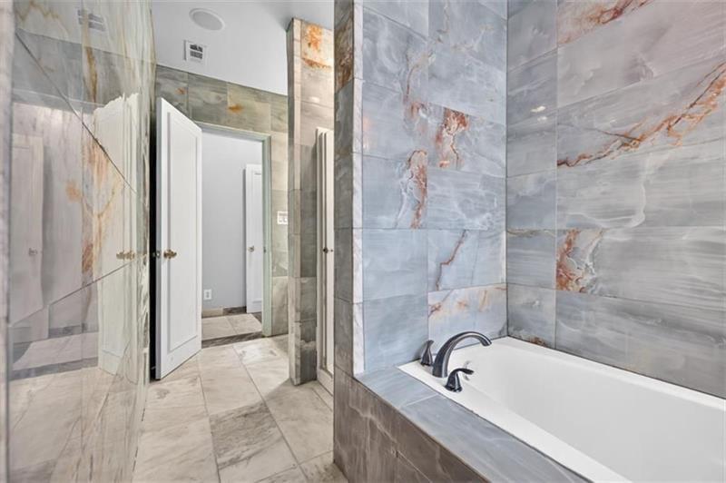 Bathroom with a built-in tub, dark faucet, and large gray marble-look tile.