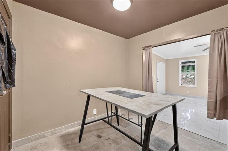 Tiled room with a large rectangular table and an open passage to a brighter adjoining room.