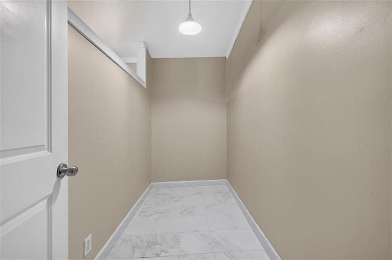 Empty walk-in closet with marble-look tile flooring and an upper shelf and hanging rod.
