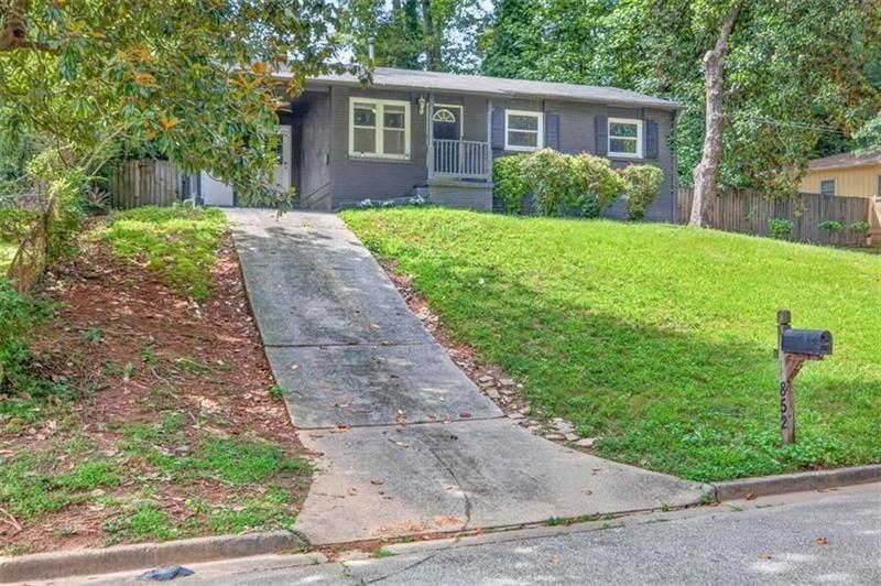 Single-story dark-sided home with a concrete driveway, green lawn, and mailbox marked 852.