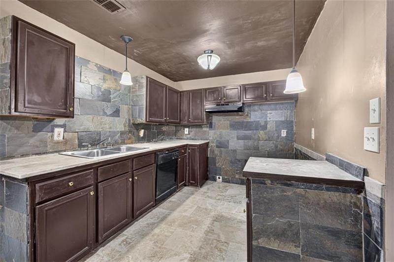 Kitchen with dark wood cabinets, gray stone tile, and a peninsula counter.