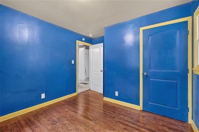 Empty room with blue walls, yellow trim, wood flooring, and an open doorway.