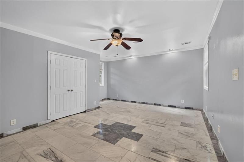 Empty room with marble-pattern tile flooring, gray walls, and a ceiling fan.