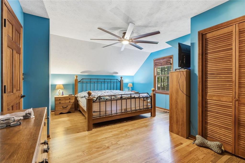 Bedroom with blue walls, hardwood floors, and a metal-frame bed beneath a ceiling fan.