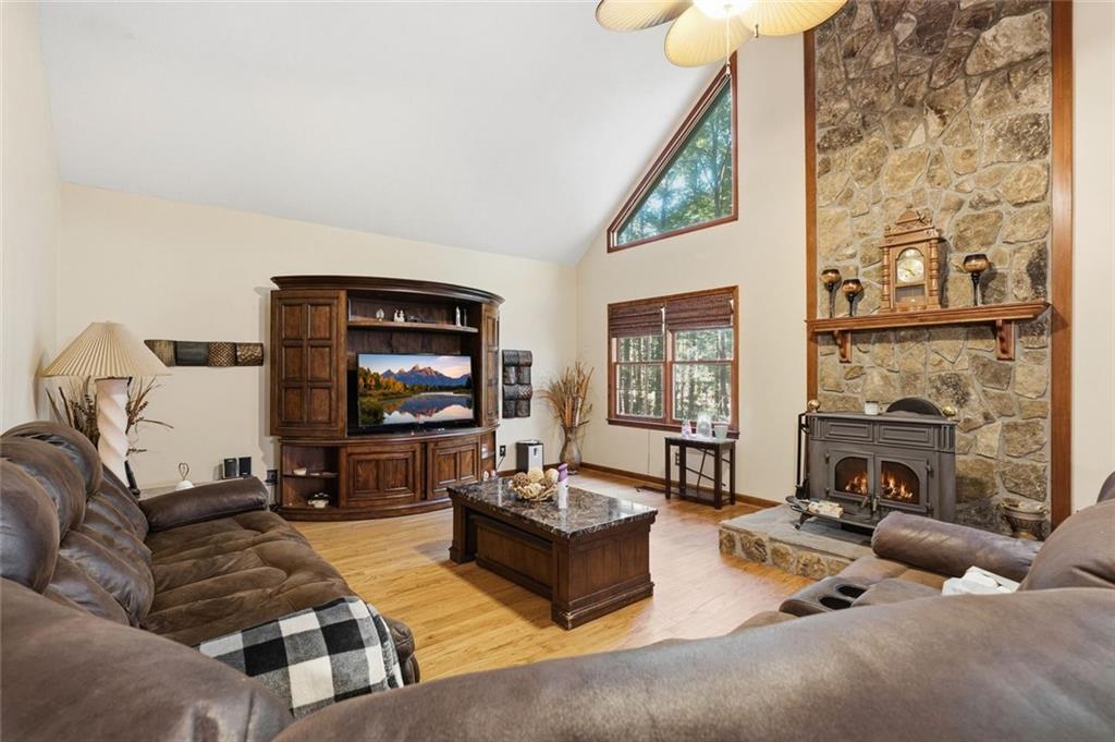Living room with a vaulted ceiling, stone fireplace, wood-burning stove, and leather sofas.